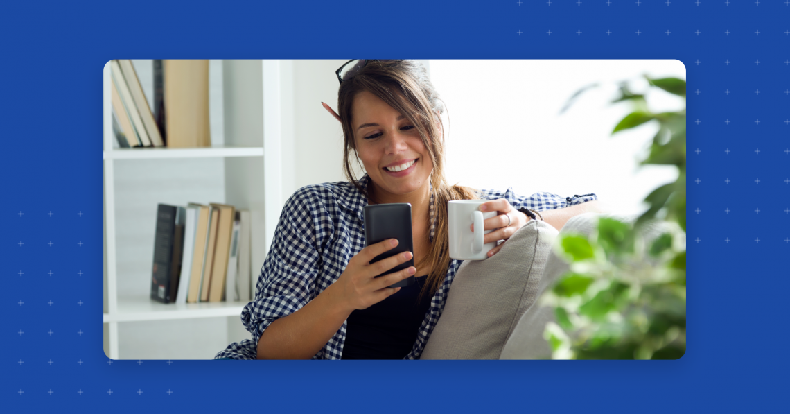 Woman on a couch drinking coffee on her mobile device