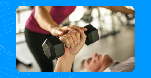 Personal trainer spotting a client as they lift weights.