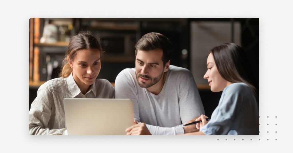 Business team researching SMS marketing platforms on a shared laptop.