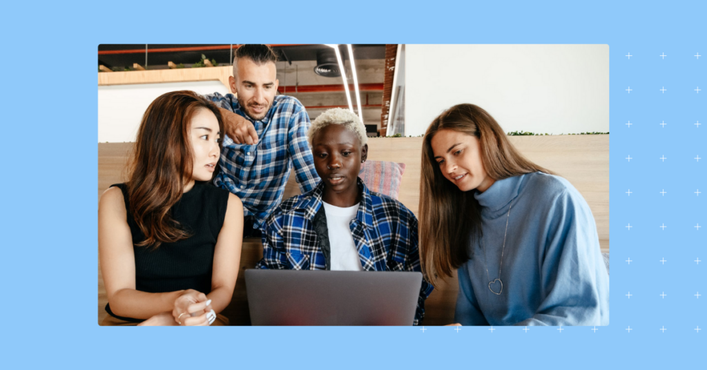 Marketing team huddled around a laptop developing a social media strategy framework.